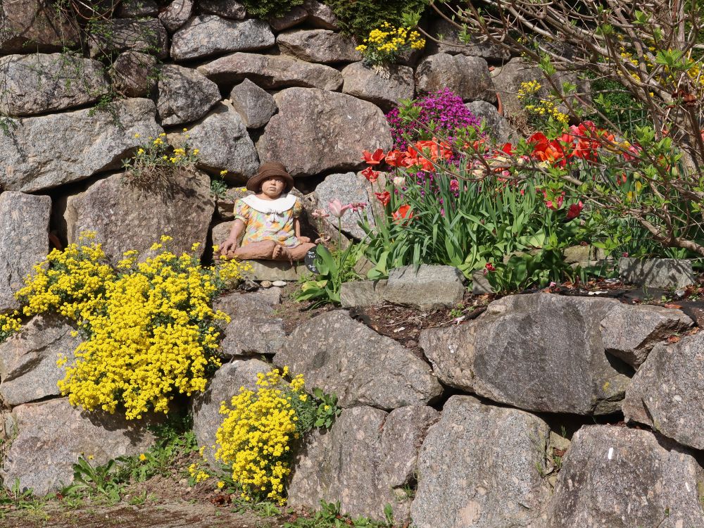 Puppe zwischen Gartenblumen