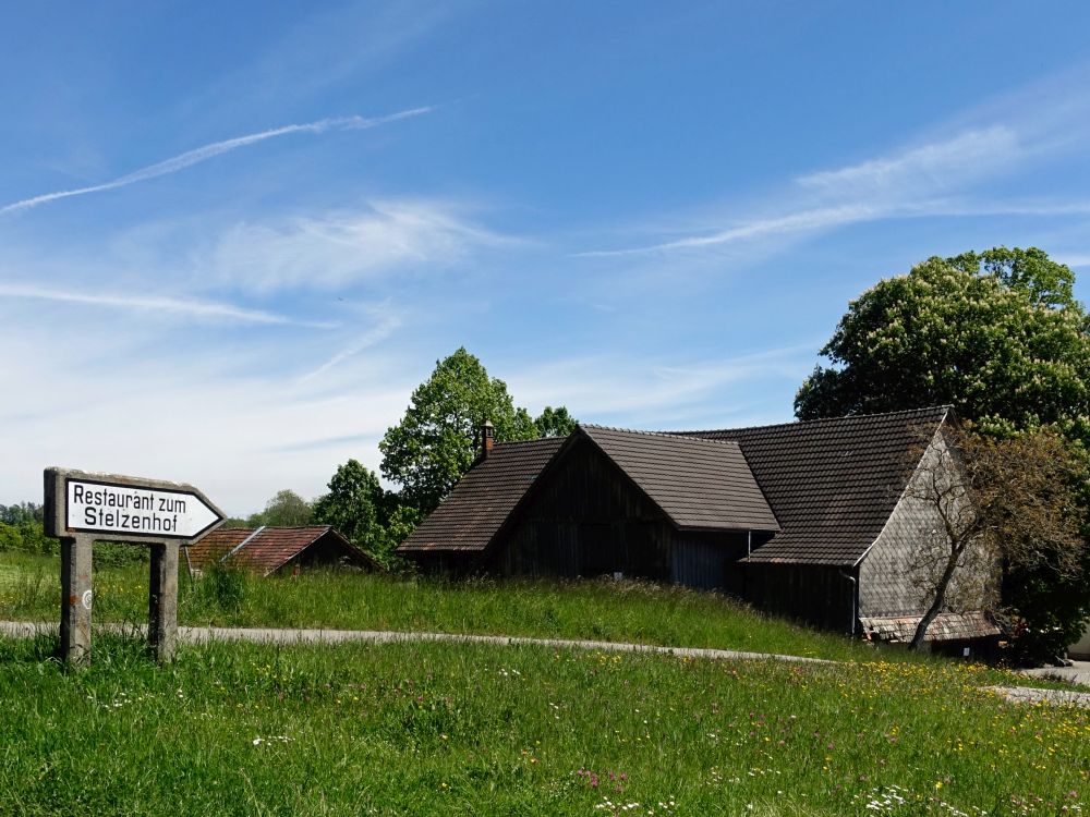 Wegweiser und altes Bauernhaus