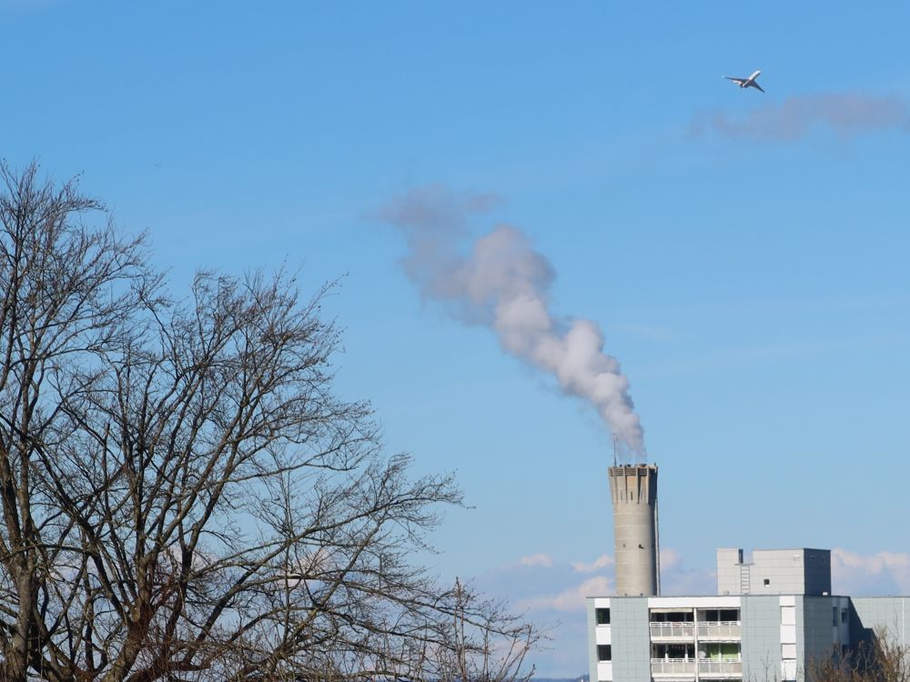 Flugzeug über rauchendem Schornstein